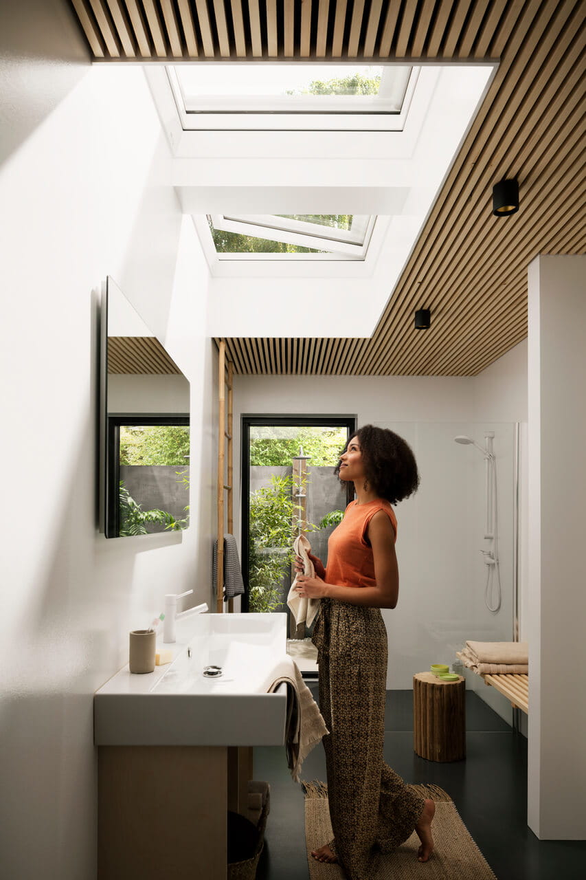 Helles, modernes Badezimmer mit VELUX Dachflächenfenstern und hölzerner Lamellendecke.