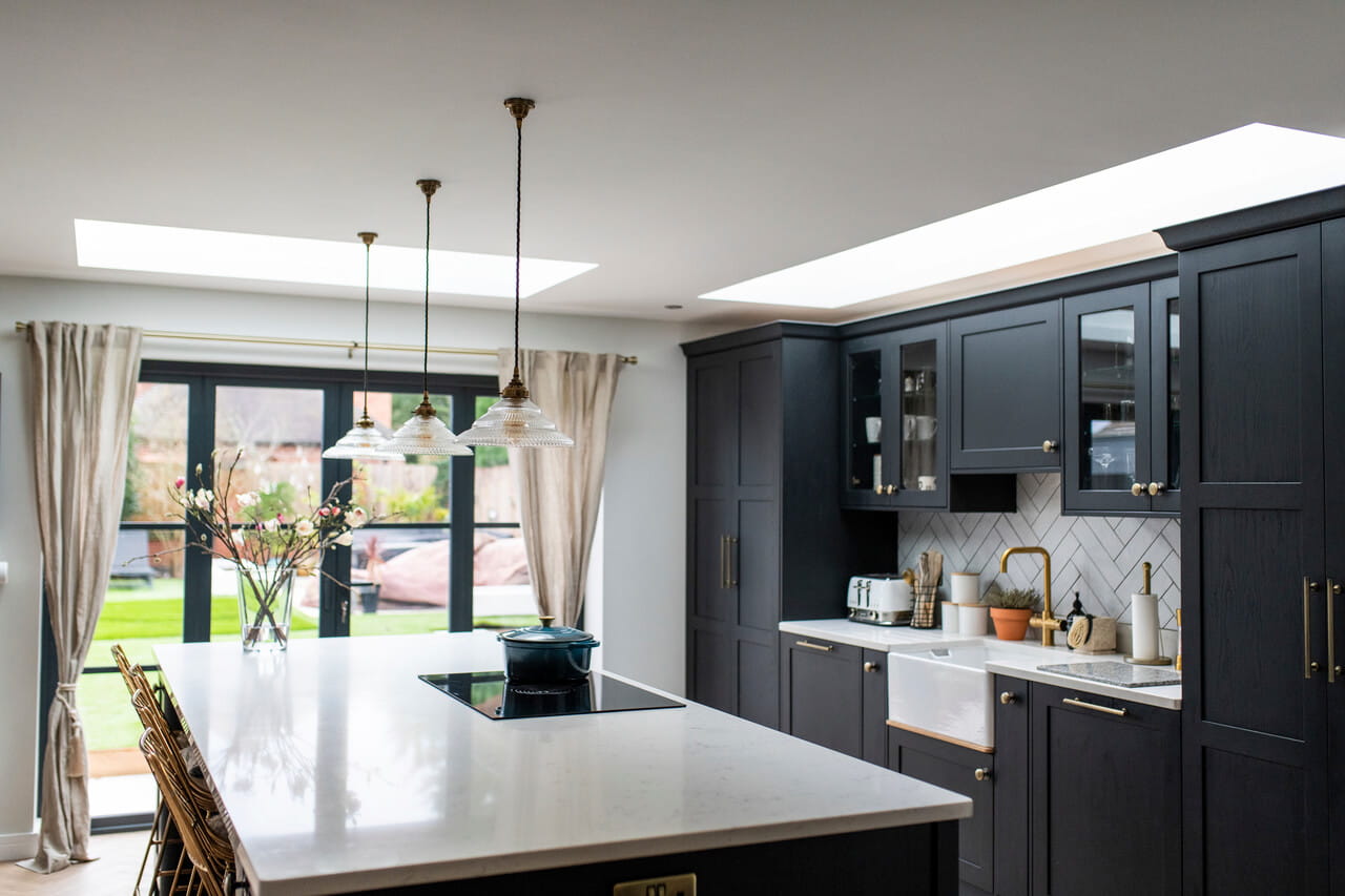 Chique keuken met donkere kasten, wit aanrecht, VELUX dakvenster en uitzicht op de tuin.