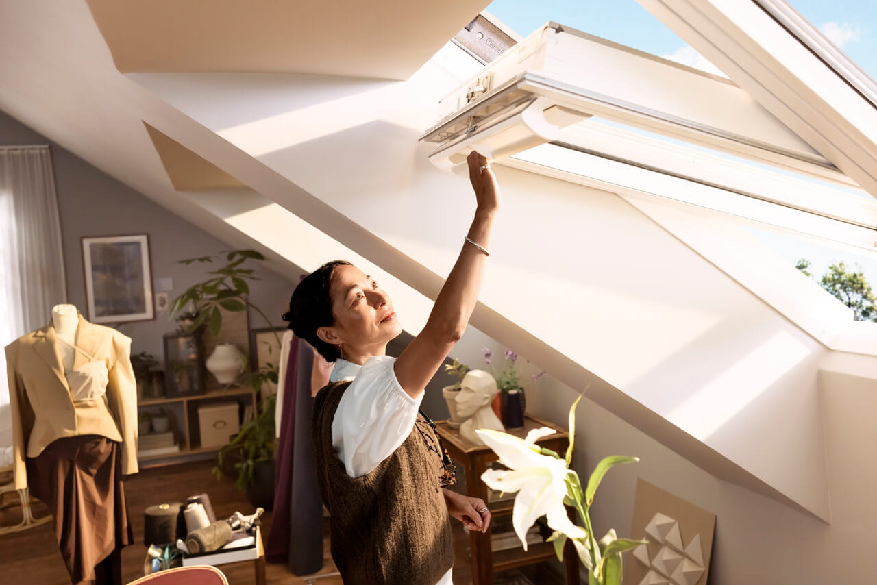 Lichte zolder thuiskantoor met open VELUX dakvenster, naaigedeelte en planten.