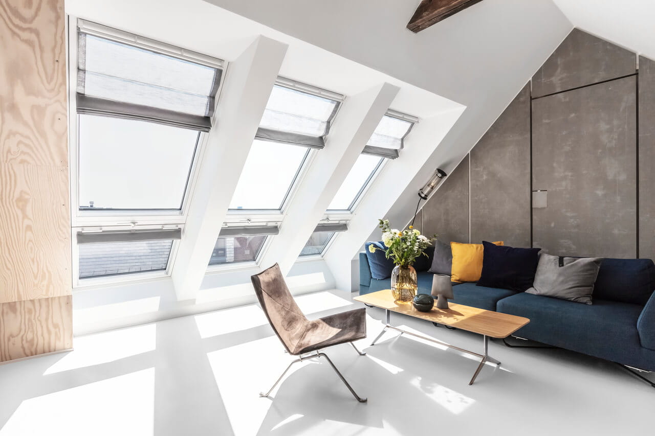 Sala de estar contemporânea no sótão com janelas de telhado VELUX e mobiliário chique.