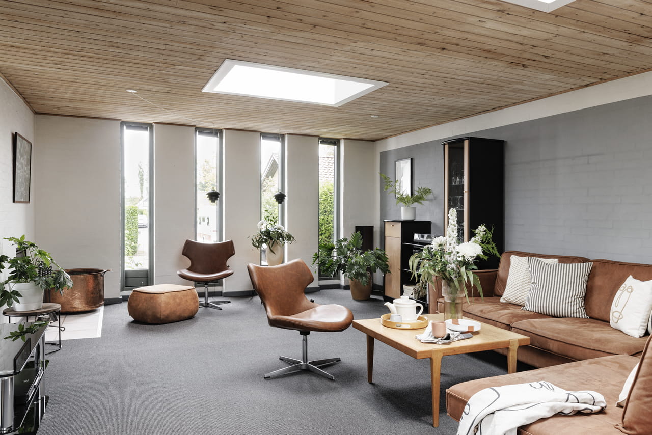 Koselig stue med VELUX takvindu, trepanel i taket og moderne møbler.