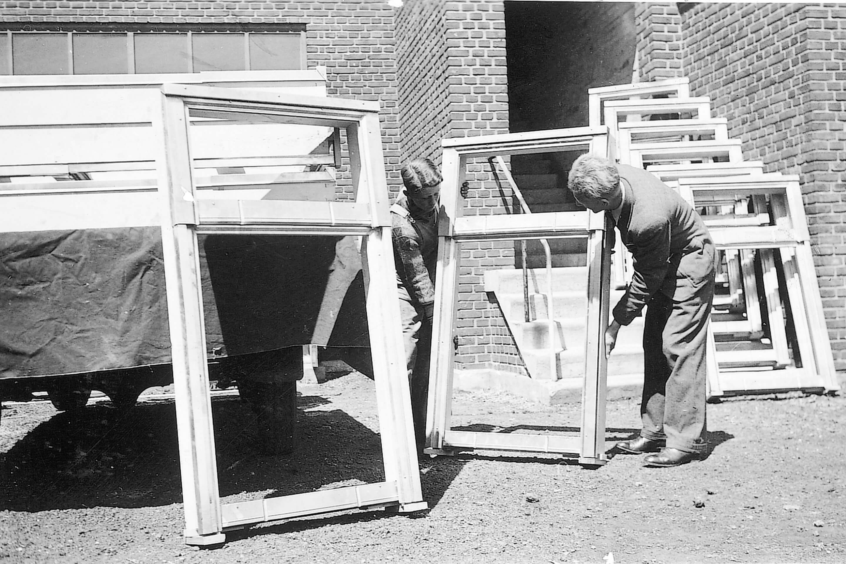 Fotografia a preto e branco de artesãos montando janelas de telhado VELUX.