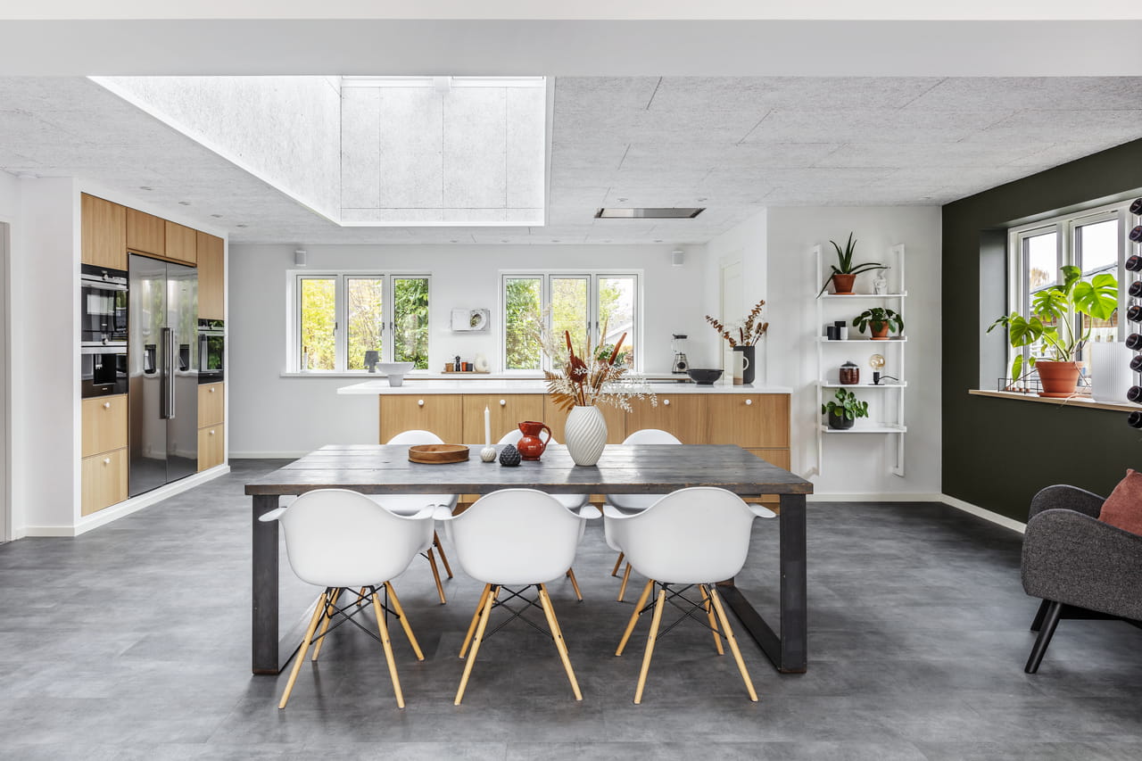 Lyst moderne køkken med VELUX ovenlysvinduer, træ-skabe og et spiseområde.