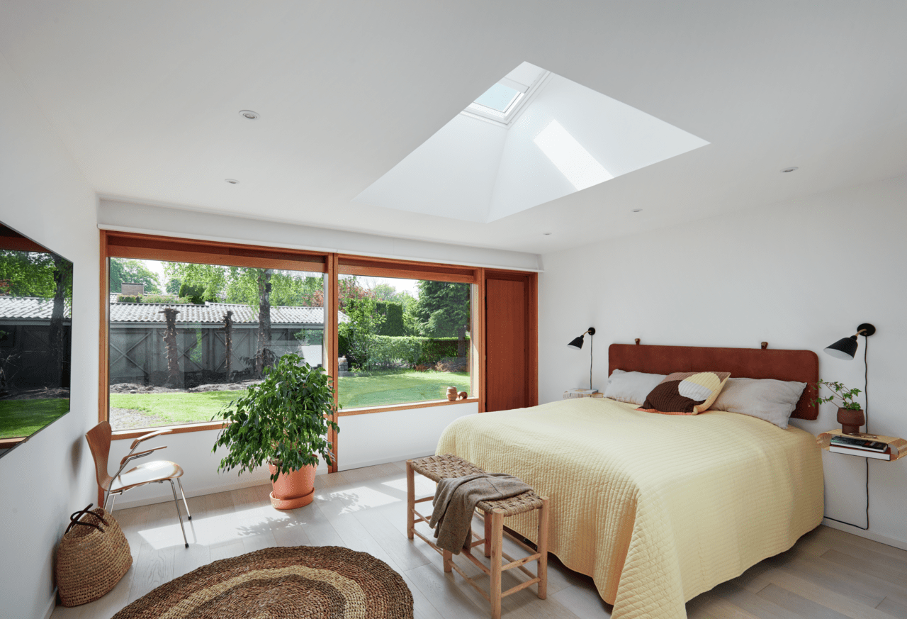 Mysigt sovrum med VELUX takfönster, utsikt över trädgården och modern inredning.