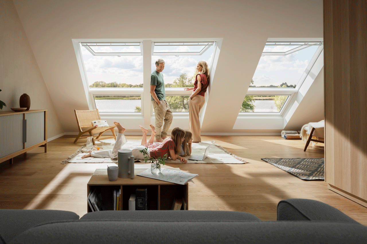 Family in a well-lit attic living room with VELUX roof windows and a serene view.