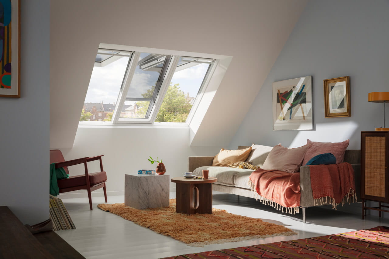 Salon moderne dans les combles avec des fenêtres de toit VELUX et une décoration élégante.