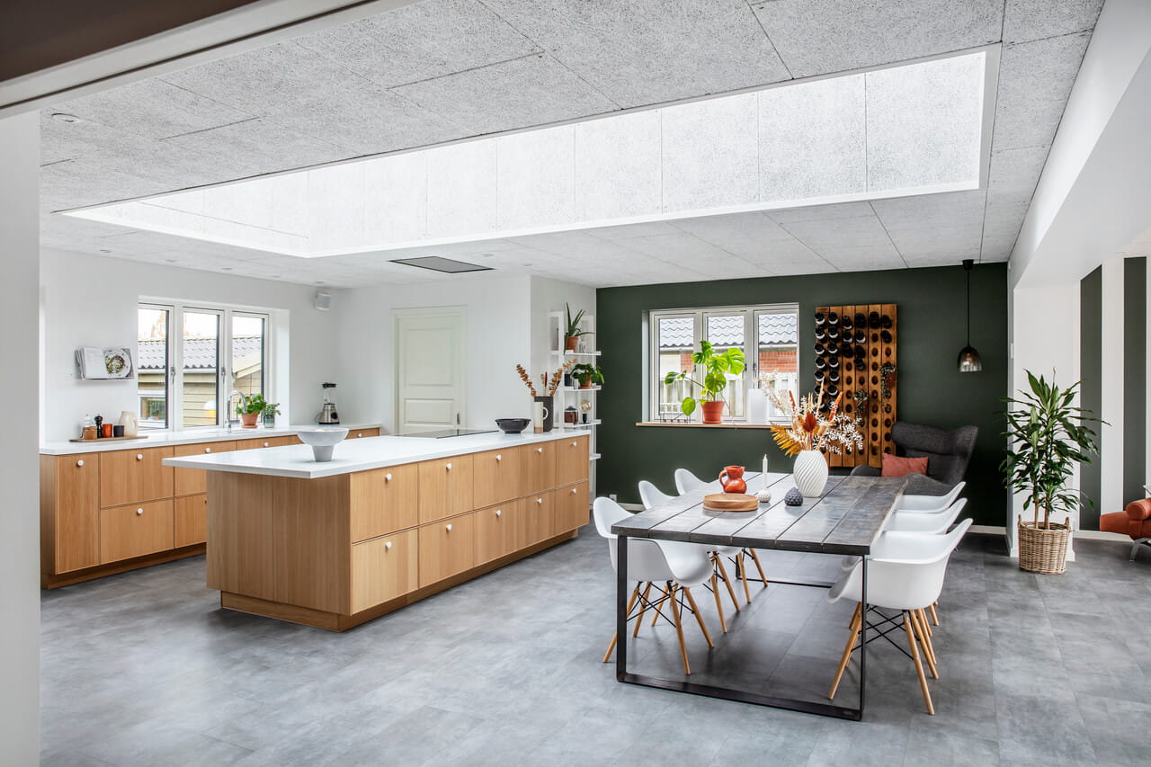 Moderne, lichte keuken met VELUX dakvenster, houten kasten en eethoek.