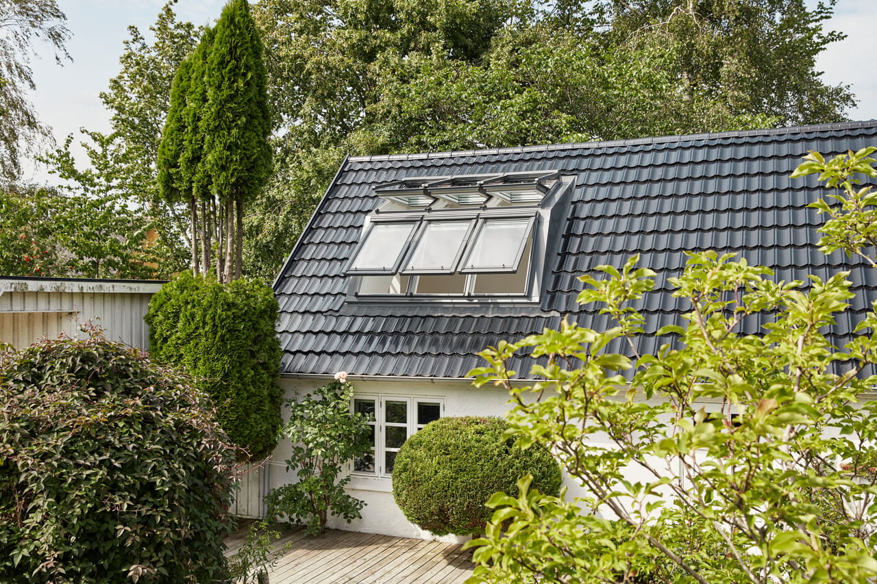 Casa residencial com janelas de telhado VELUX rodeada por árvores