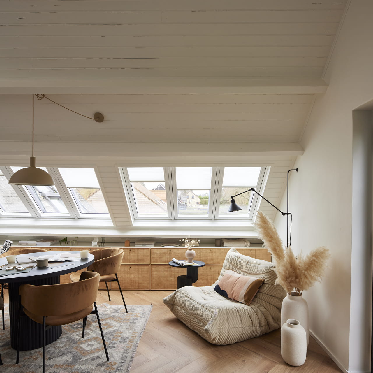 Lys loftstue med VELUX-vinduer, trepanel i taket og moderne møbler.