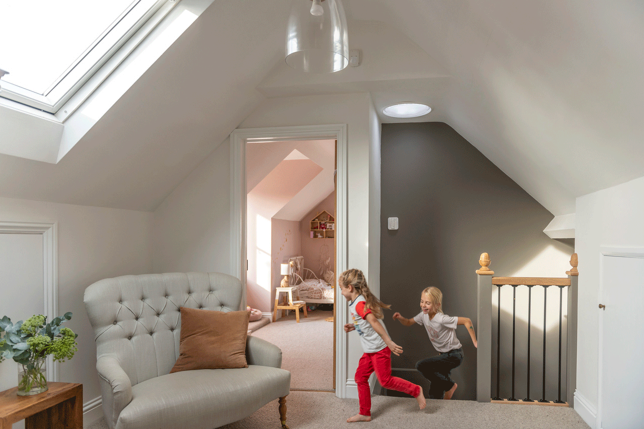 Attic playroom with VELUX roof window, toys, and a beige armchair.