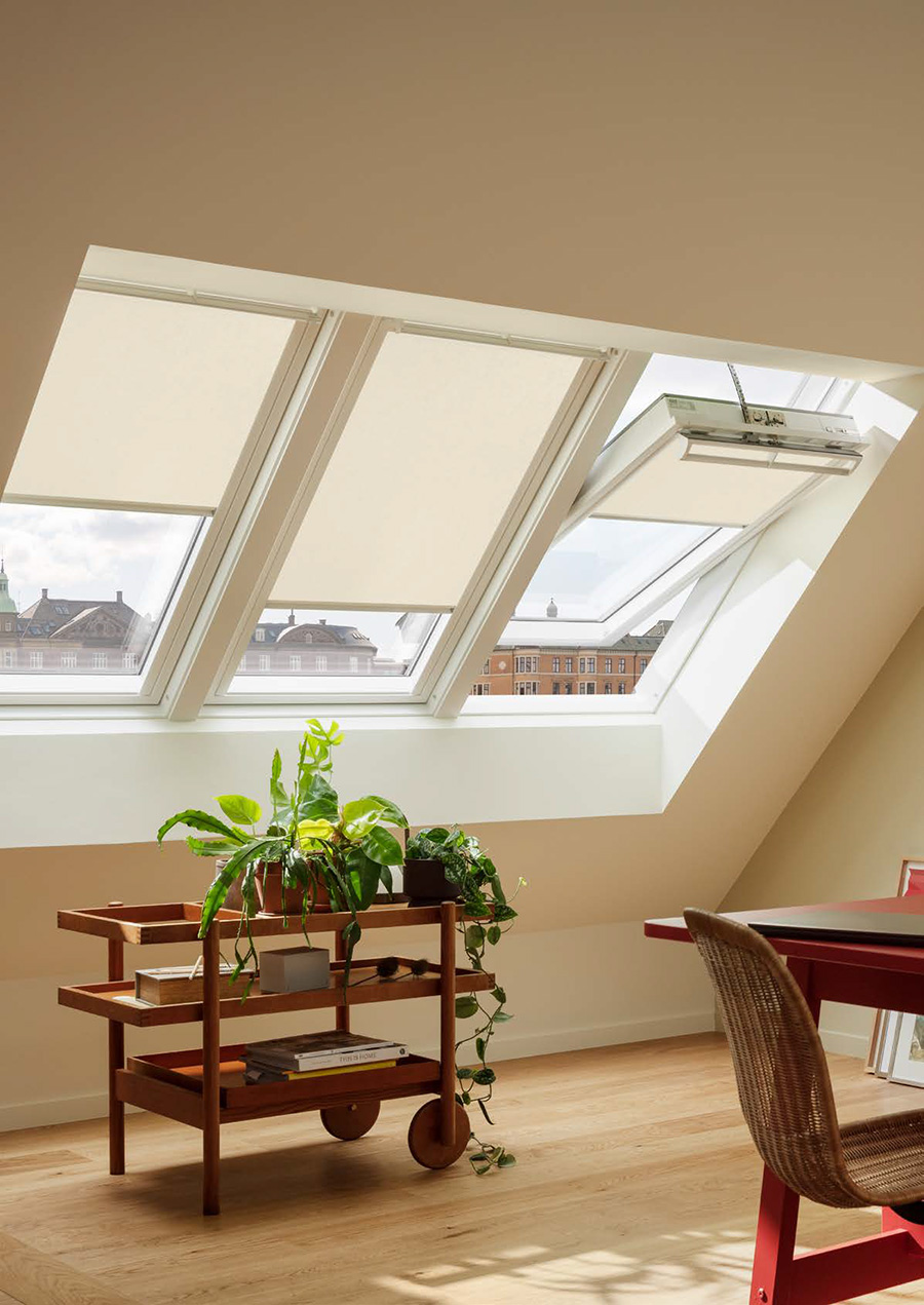 Dachboden-Heimbüro mit VELUX Dachflächenfenster, Pflanzenwagen und rotem Schreibtisch.