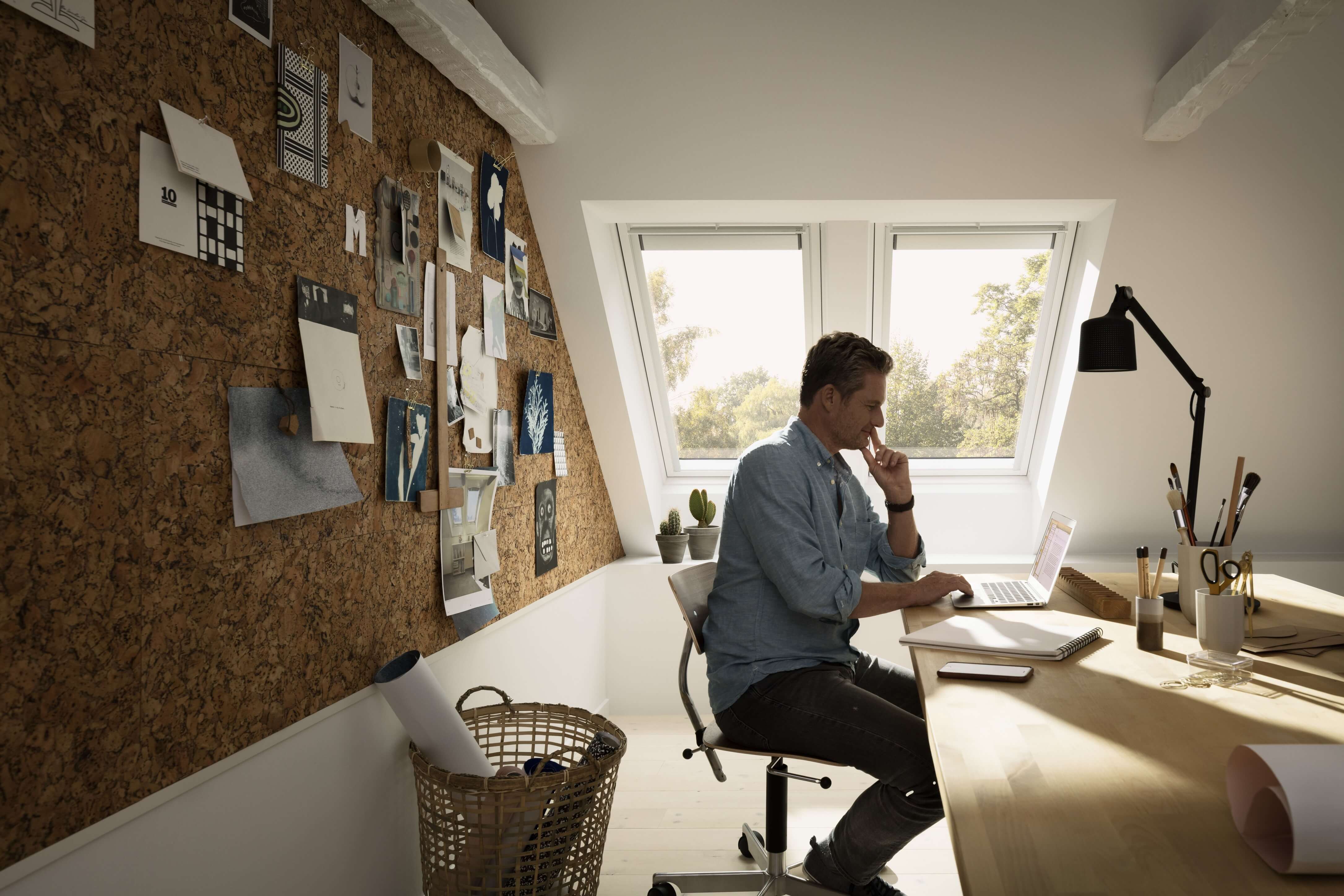 Geräumiges Home-Office mit hölzernem Schreibtisch, Inspirationstafel und VELUX Dachflächenfenster.