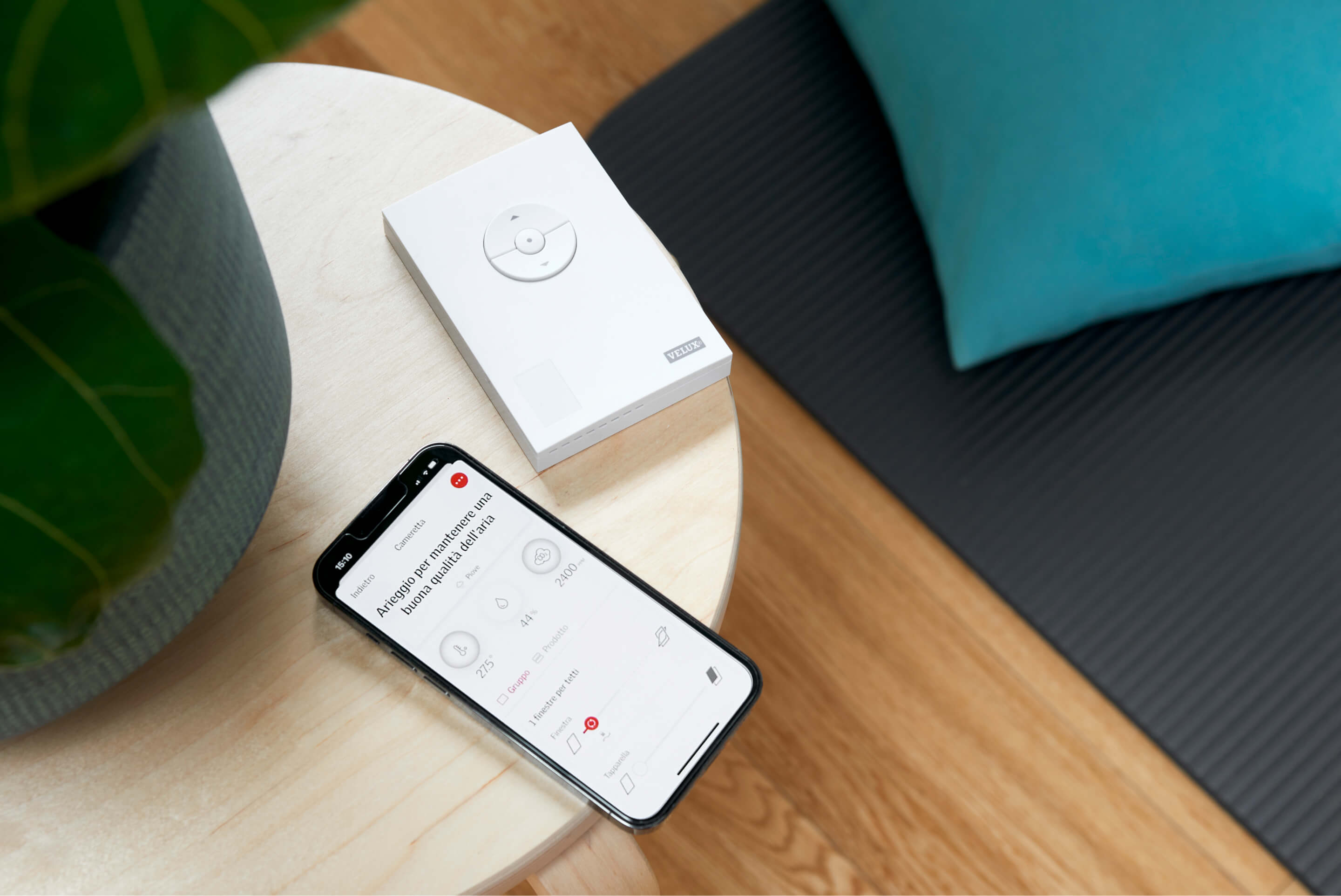 Smartphone mit einer App zur Heim-Kontrolle neben einem verpackten Smart-Gerät auf einem Tisch.