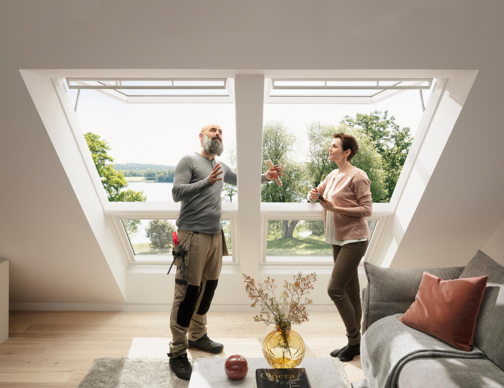 Modernes Wohnzimmer mit VELUX Dachflächenfenster mit Seeblick, mit zwei Personen in der Nähe des Fensters.