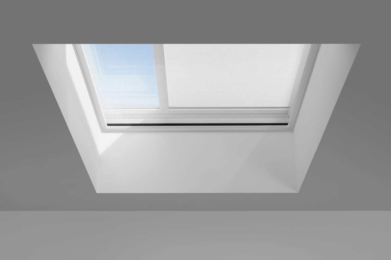 Modernes VELUX Dachflächenfenster in einer schrägen Decke mit Aussicht auf den blauen Himmel.