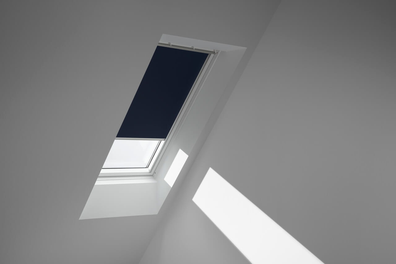 Minimalistisches Zimmer mit einem VELUX Dachflächenfenster, das Sonnenlicht an die Wand wirft.