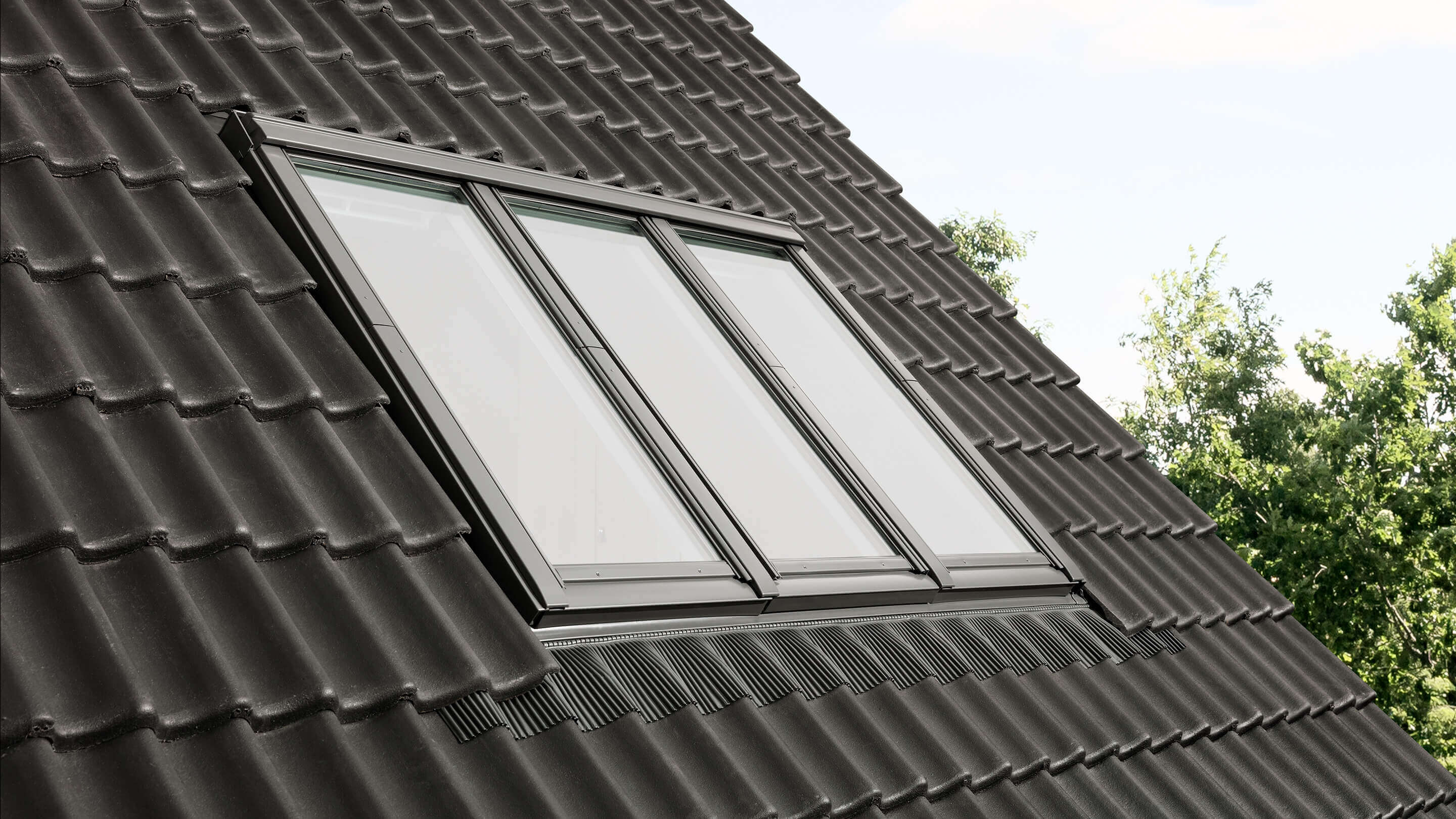 VELUX Dachflächenfenster auf dunklem Ziegeldach, vereinen Stil und Funktionalität.