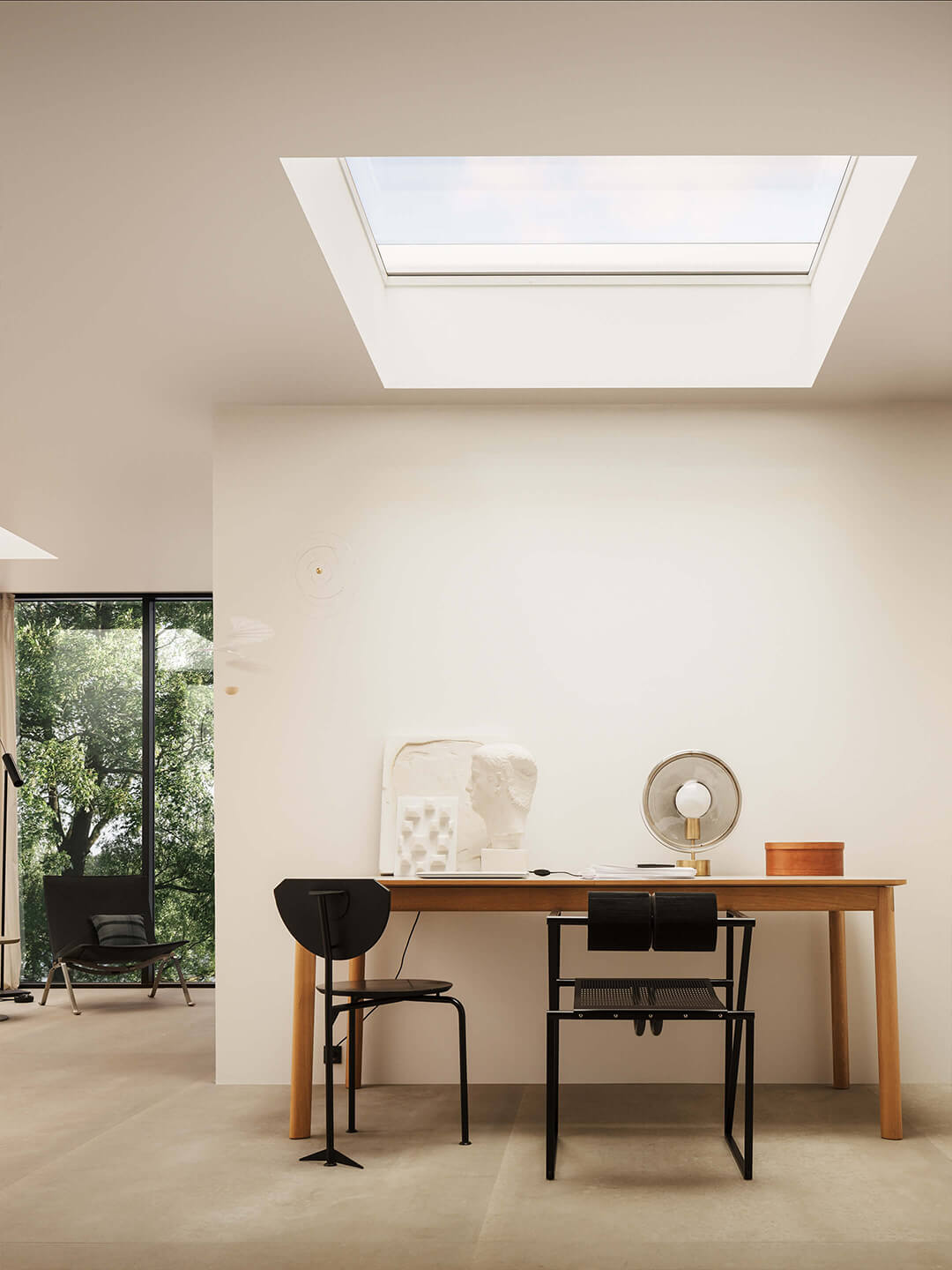 Modernes Homeoffice mit hölzernem Schreibtisch, schwarzem Stuhl und VELUX Dachflächenfenster, das für natürliches Licht sorgt.