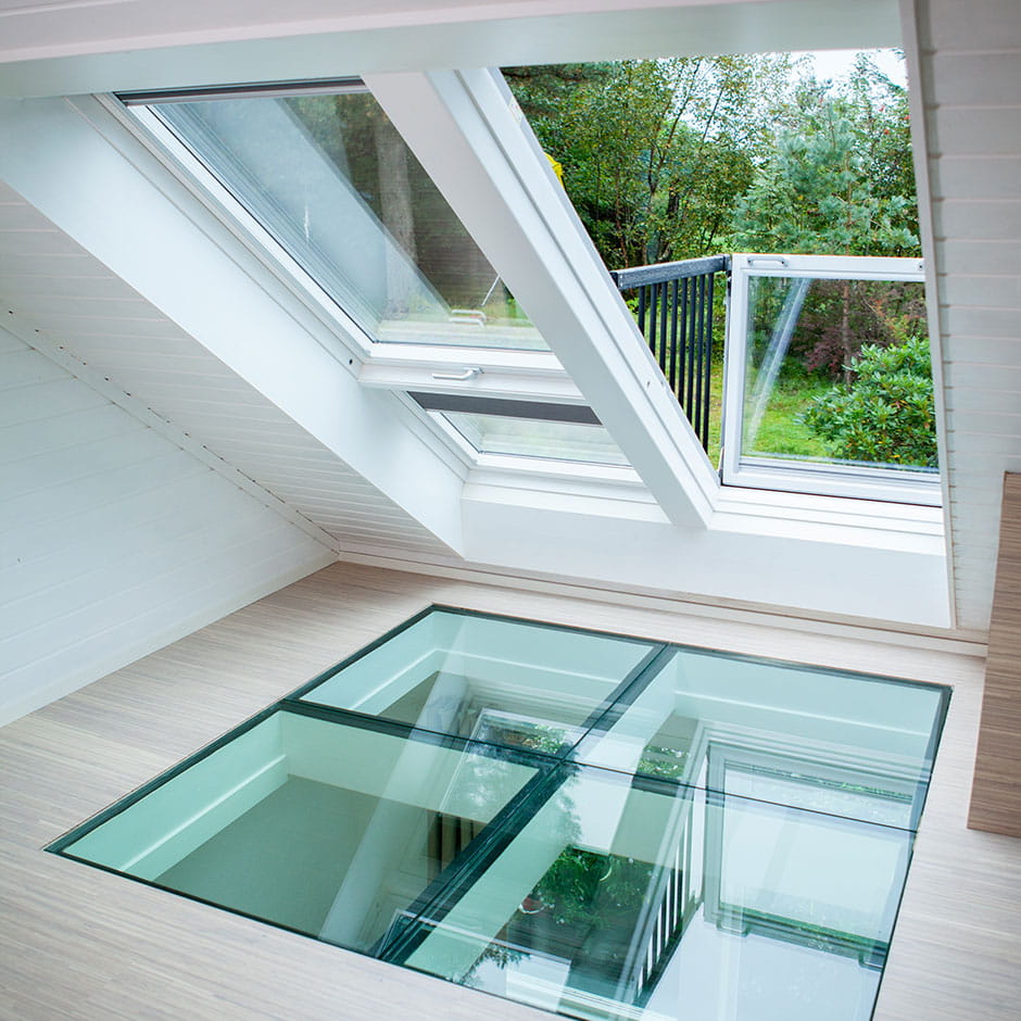 Dachboden mit VELUX Dachflächenfenster offen zur Grünanlage und einer klaren Glas-Bodenplatte.