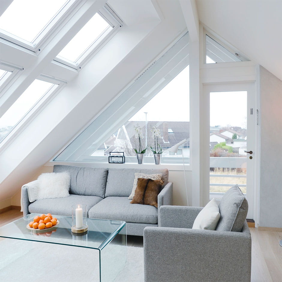 Gemütliches Wohnzimmer im Dachboden mit natürlichem Licht von VELUX Dachflächenfenstern, modernen Möbeln und Pflanzen.