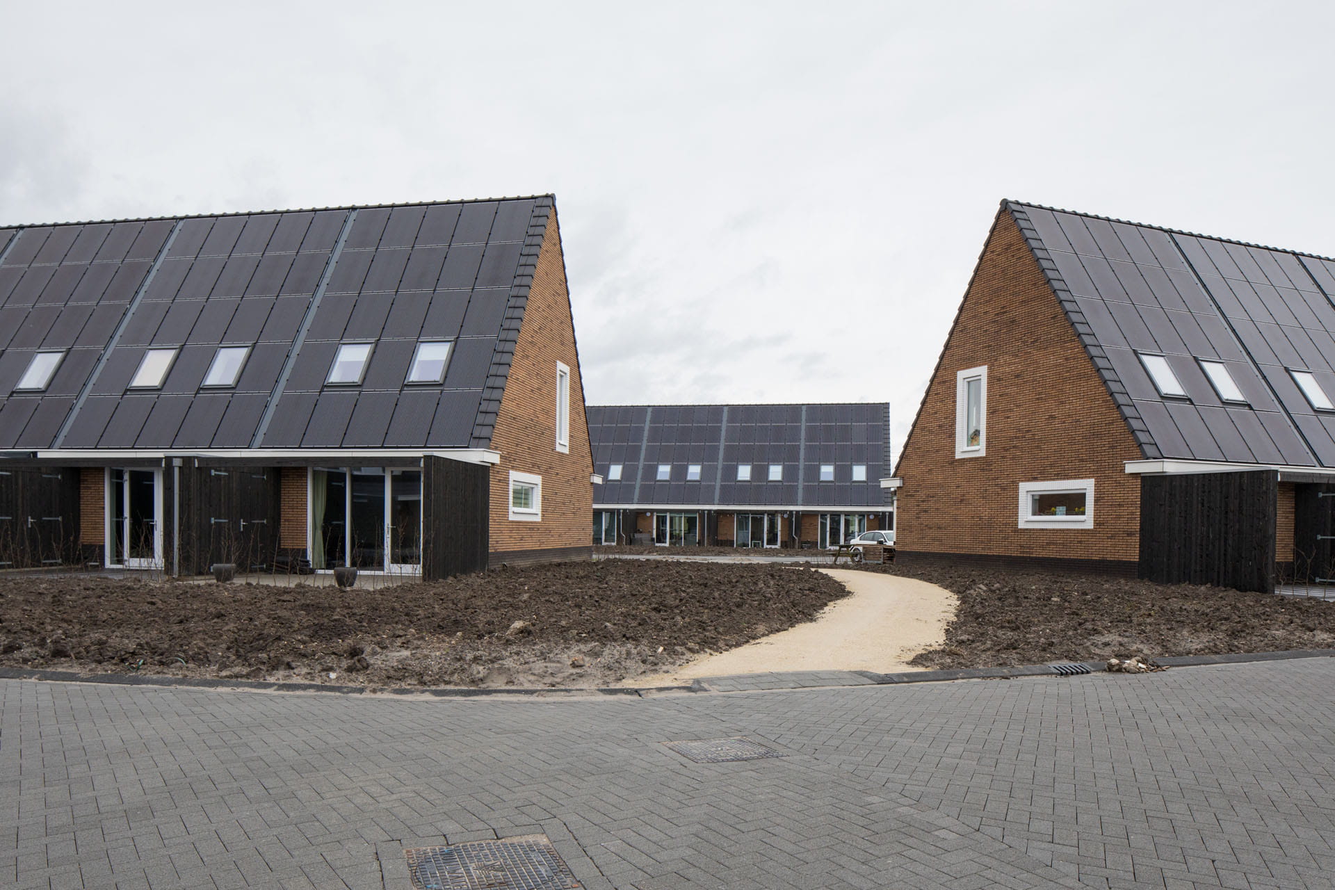 Moderne Reihenhäuser mit Solarpaneelen und VELUX Dachflächenfenstern, die die Nachhaltigkeit hervorheben.