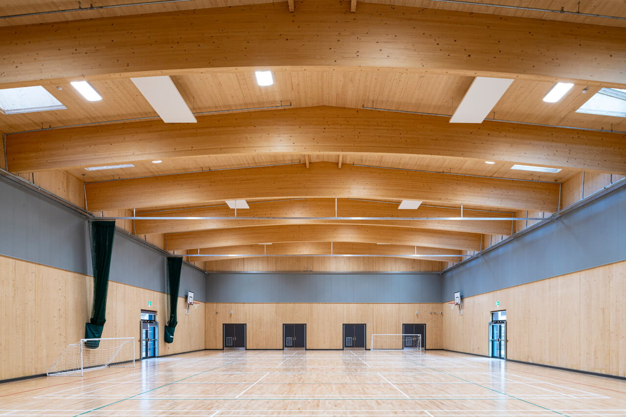 Geräumige Sporthalle mit VELUX Dachflächenfenster und hölzernem Innendesign.