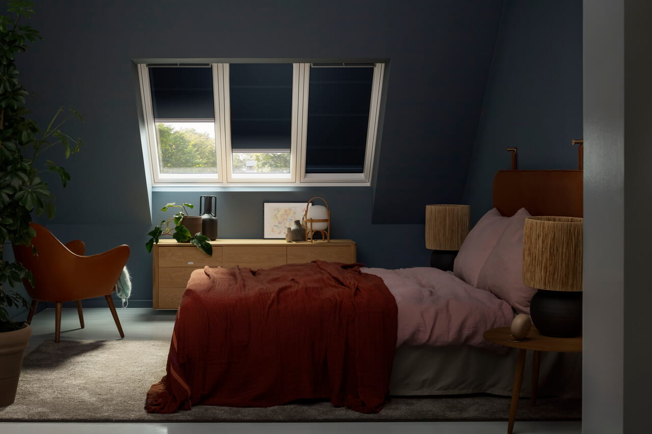 Ruhiges Schlafzimmer mit VELUX Dachflächenfenster, kuscheliger Bettwäsche und natürlichen Holzakzenten.