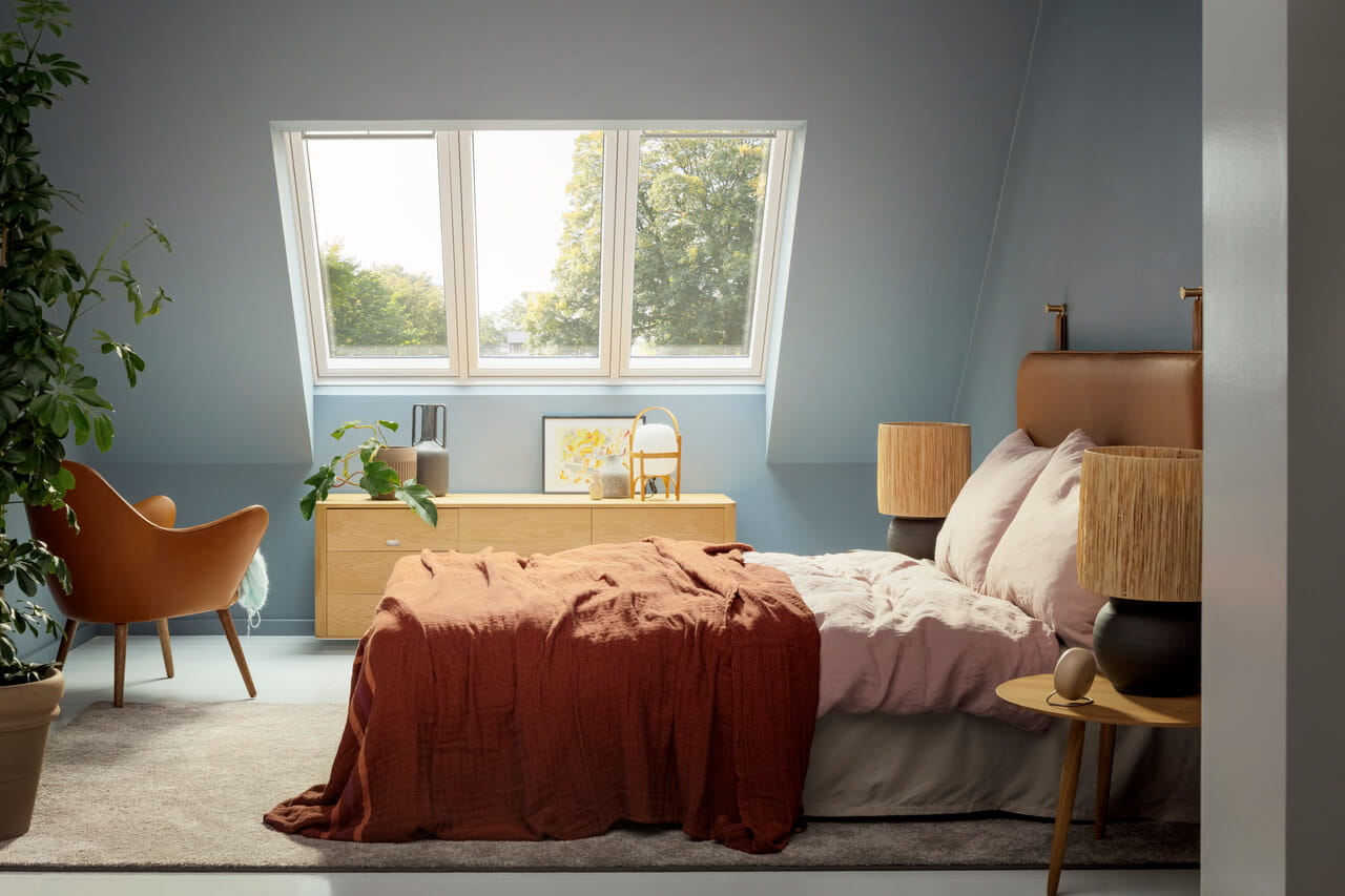 Gemütliches Schlafzimmer mit Terrakotta-Bettüberwurf und natürlichem Licht von VELUX Dachflächenfenster.