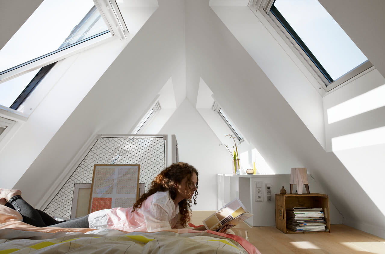 Gemütliches Schlafzimmer im Dachboden mit natürlichem Licht von VELUX Dachflächenfenstern und minimalistischer Dekoration.