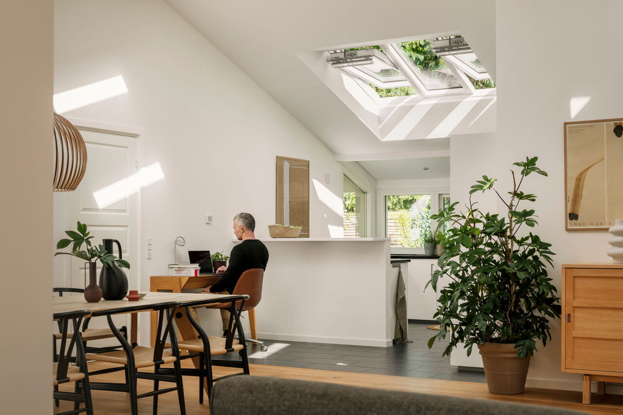 Modernes Homeoffice mit natürlichem Licht von VELUX Dachflächenfenstern und angrenzender Küche.