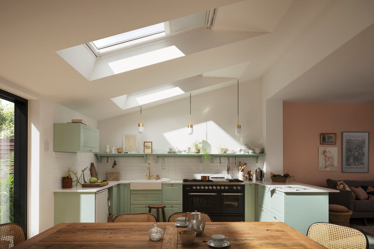 Gemütliche Küche mit VELUX Dachflächenfenstern und pastellgrünen Schränken.