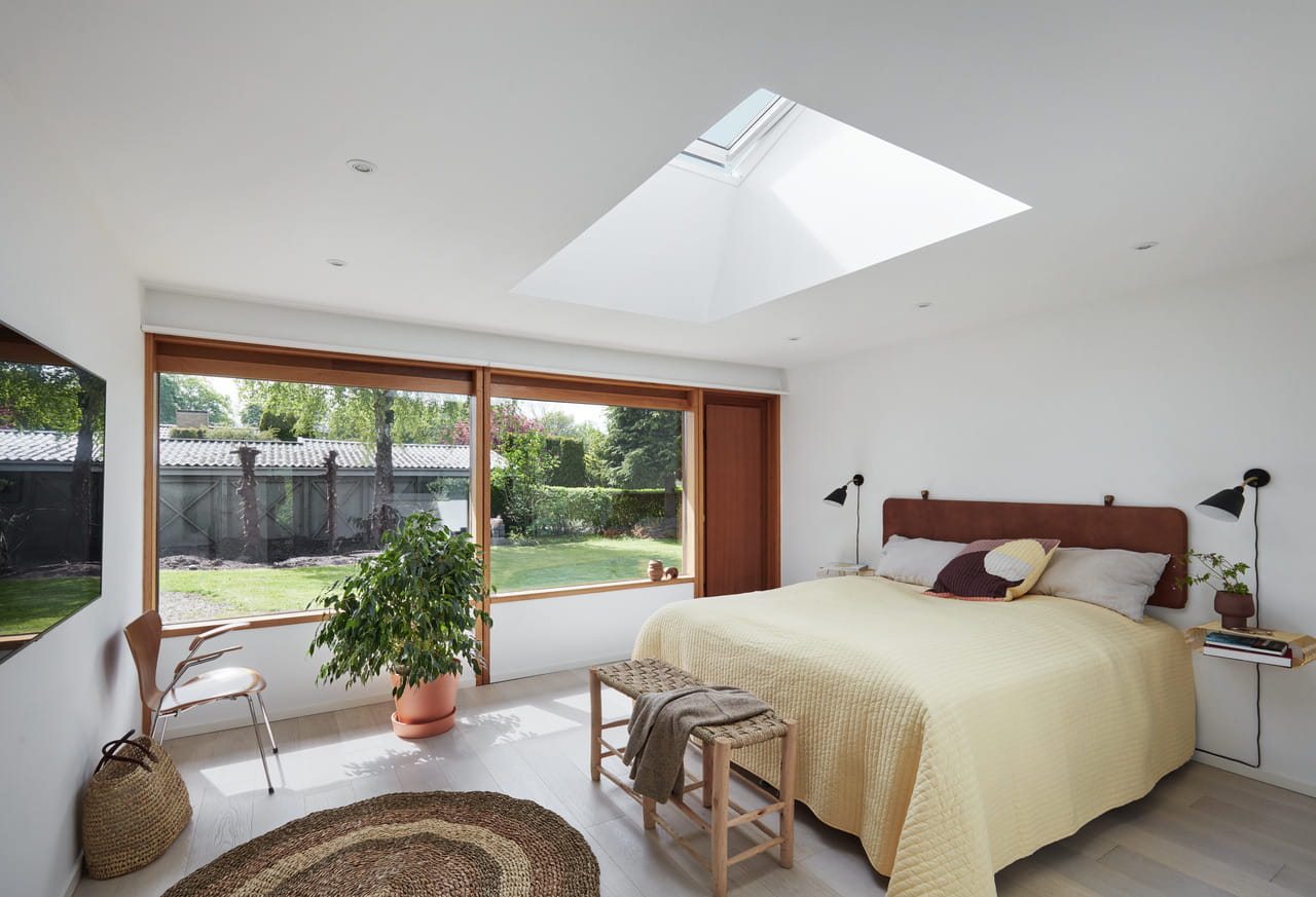 Modernes Schlafzimmer mit natürlichem Licht von VELUX Dachflächenfenster und Gartenblick.