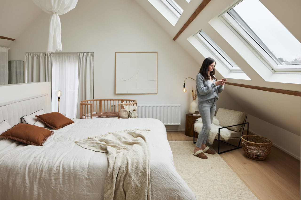 Gemütliches Dachboden-Schlafzimmer mit Bett, Kinderbett und natürlichem Licht von VELUX Dachflächenfenstern.