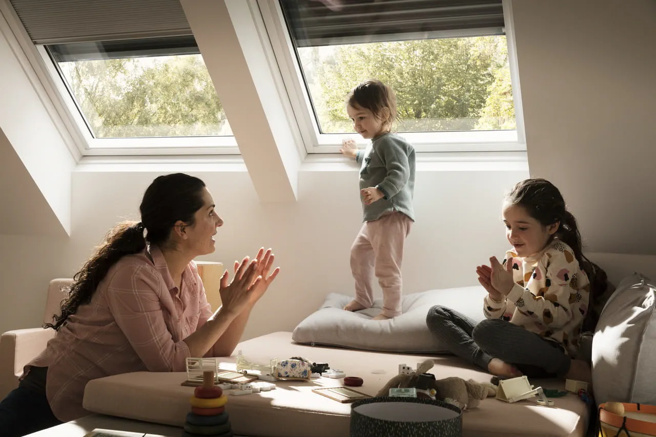 Salon confortable avec la famille et des jouets, éclairé par la lumière naturelle d'une fenêtre de toit VELUX.