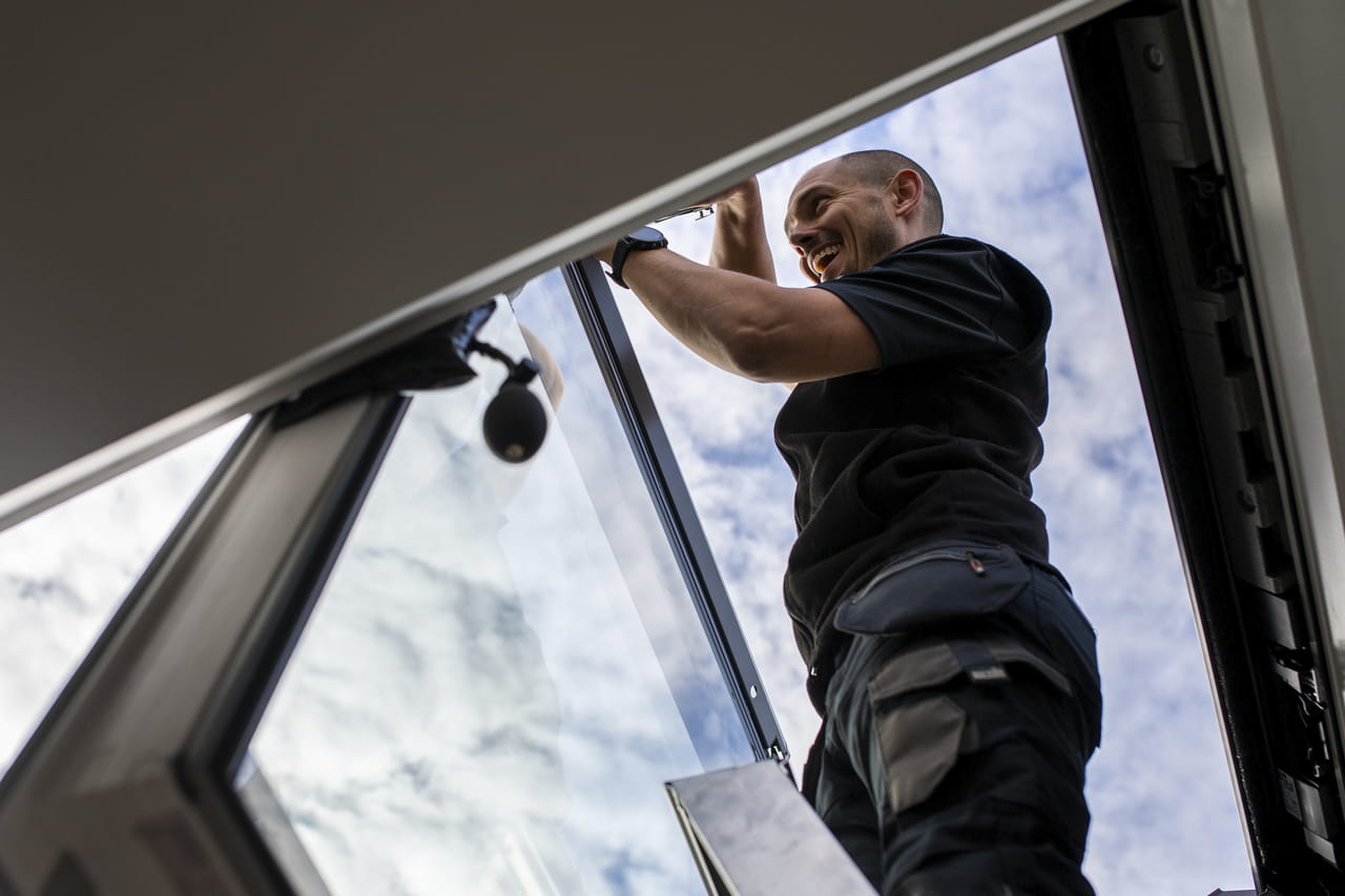Professional installer fitting a VELUX roof window from an inside perspective.