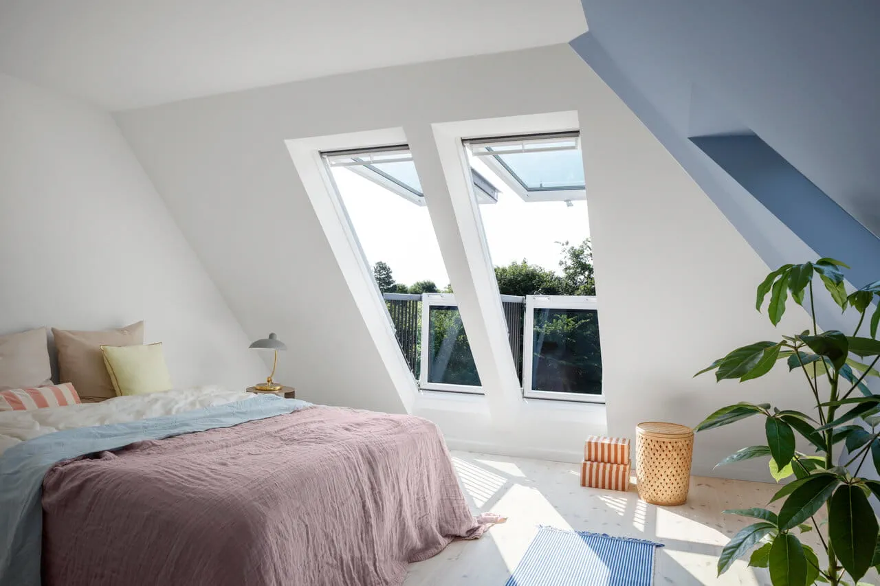 Chambre mansardée confortable avec fenêtres de toit VELUX et décoration minimaliste.