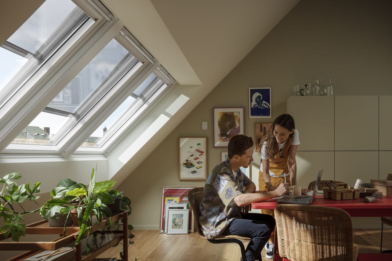 Bureau à domicile dans le grenier avec des fenêtres de toit VELUX, des plantes et un agencement moderne du bureau.