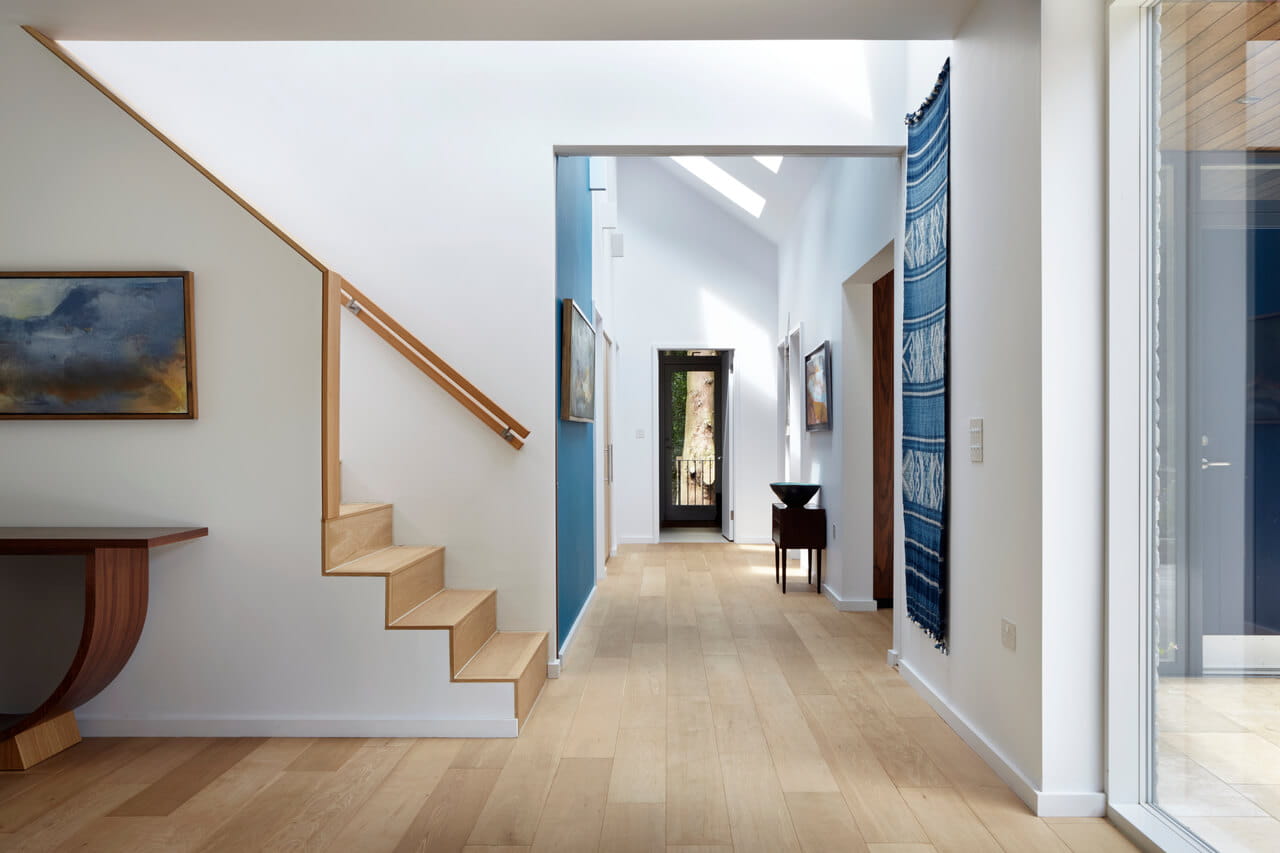 Corridoio moderno e luminoso con scala in legno, arte sulle pareti e finestra per tetti VELUX.