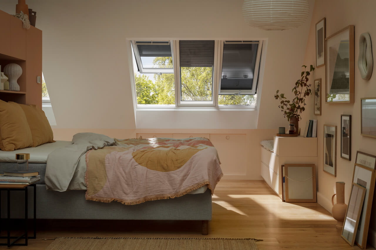 Chambre sereine avec lit, art, plantes et lumière naturelle provenant des fenêtres de toit VELUX.