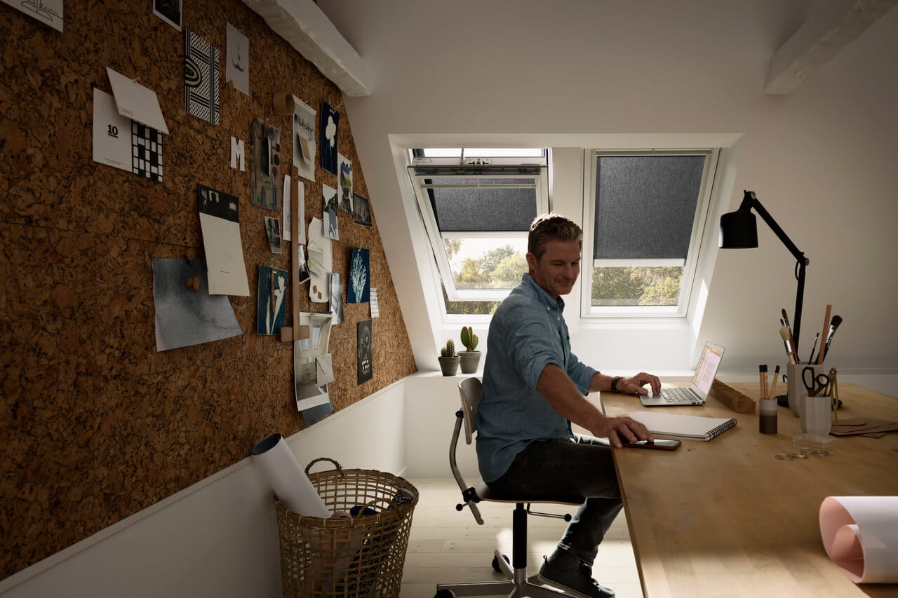 Amplio despacho en casa con escritorio de madera, herramientas creativas y una ventana de tejado VELUX.