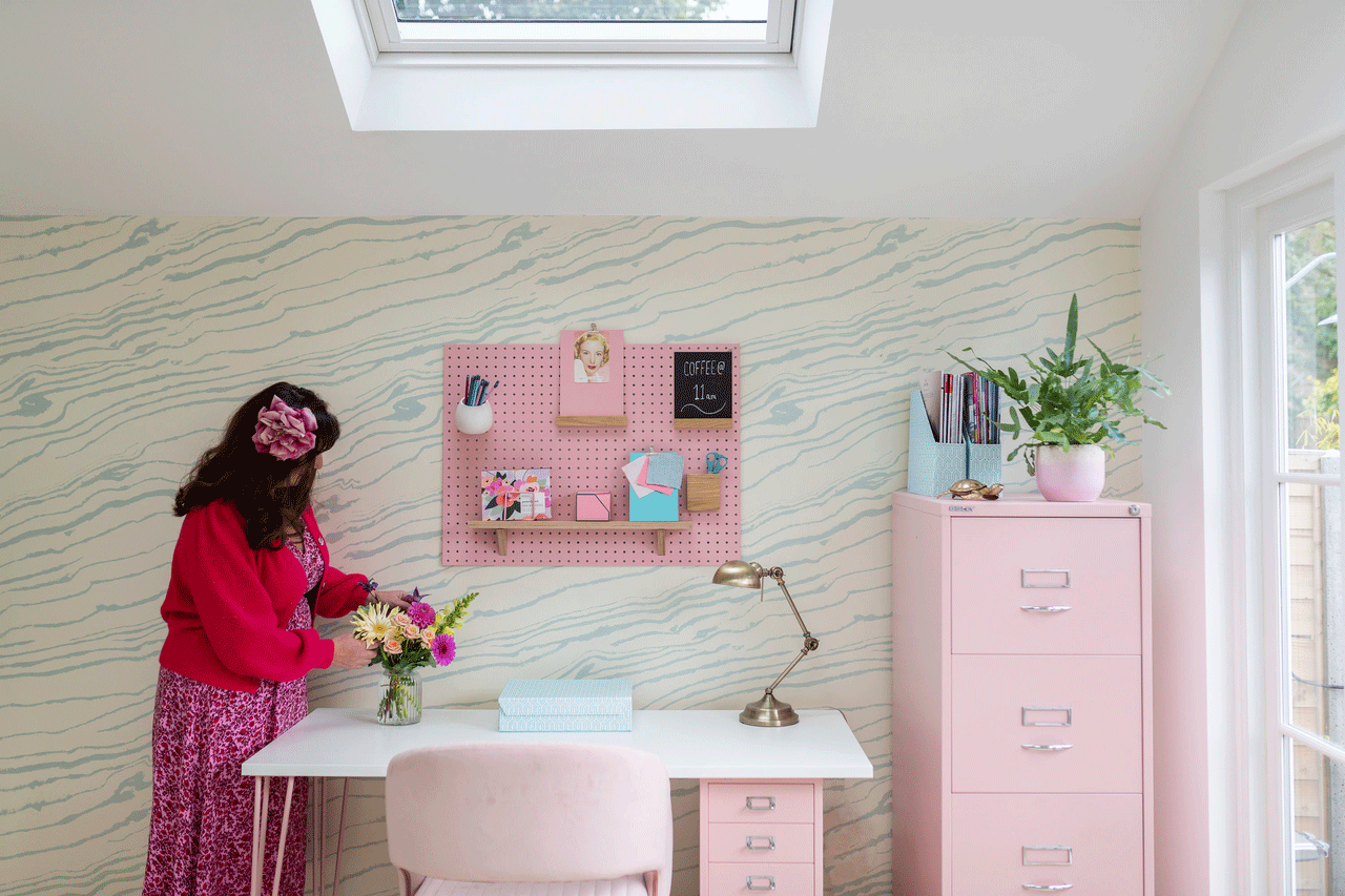 Bright home office with pink decor, white desk, VELUX skylight, and wavy wallpaper.