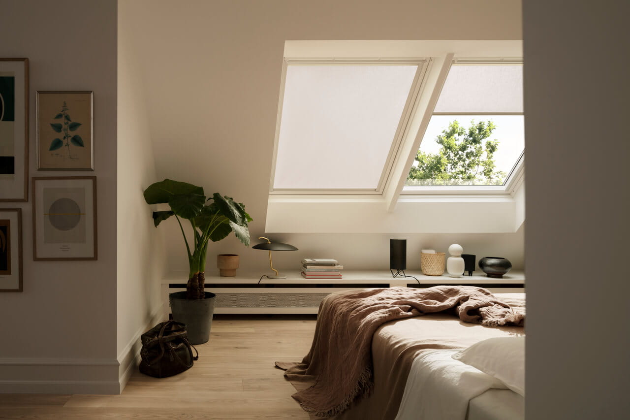 Chambre douillette avec une fenêtre de toit VELUX, une décoration minimaliste et un plaid chaud sur le lit.