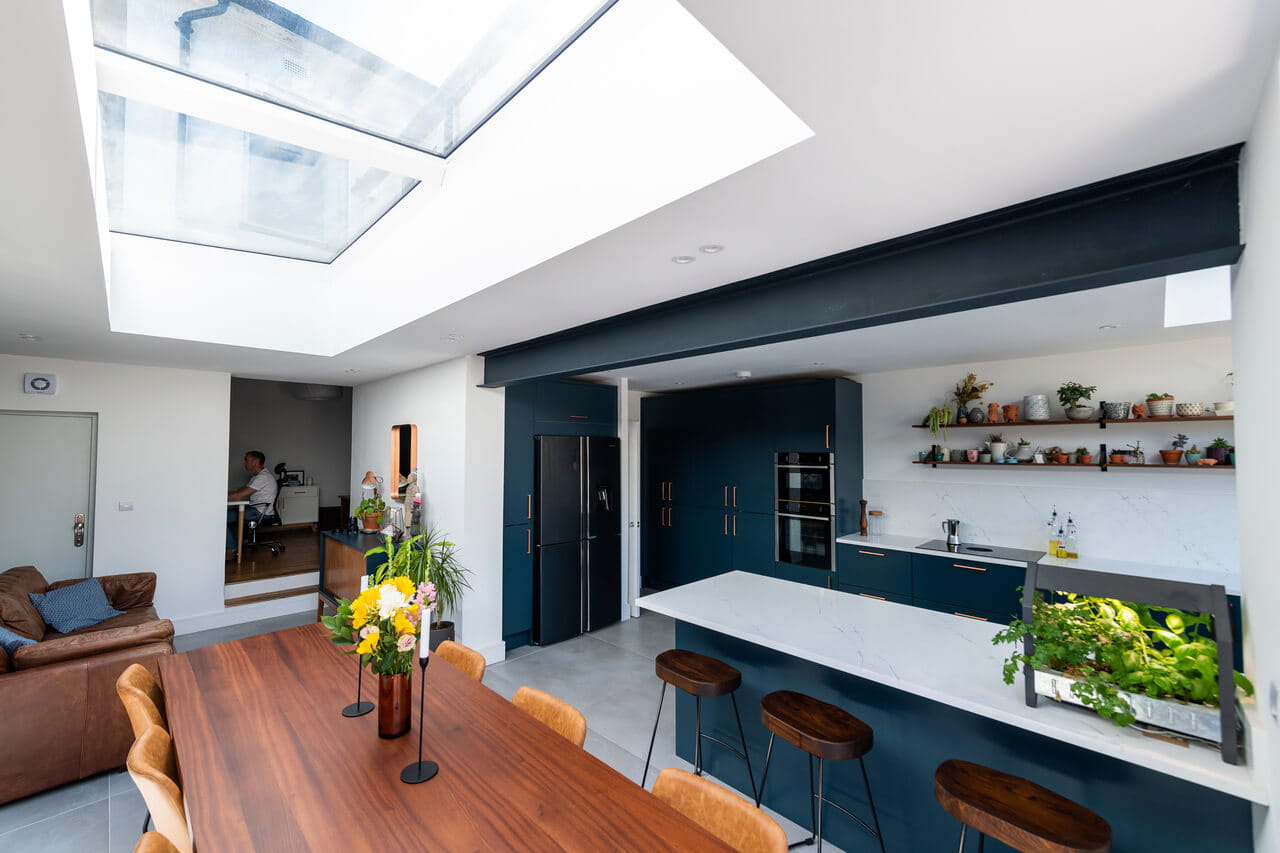 Cozinha contemporânea com janela de telhado VELUX e armários azul-escuro.