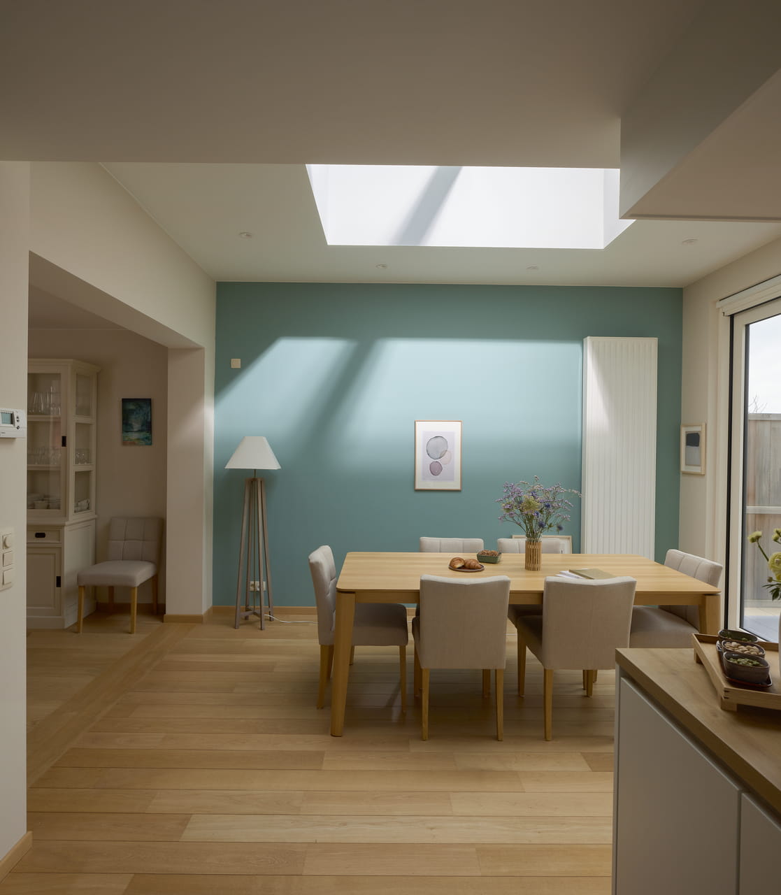 Moderne eetkamer met natuurlijk licht van VELUX dakvenster, houten vloeren en eenvoudige decoratie.