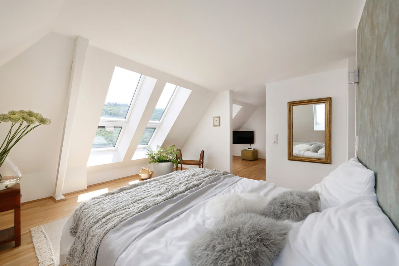 Lichte zolder slaapkamer met VELUX dakvensters en gezellige inrichting.