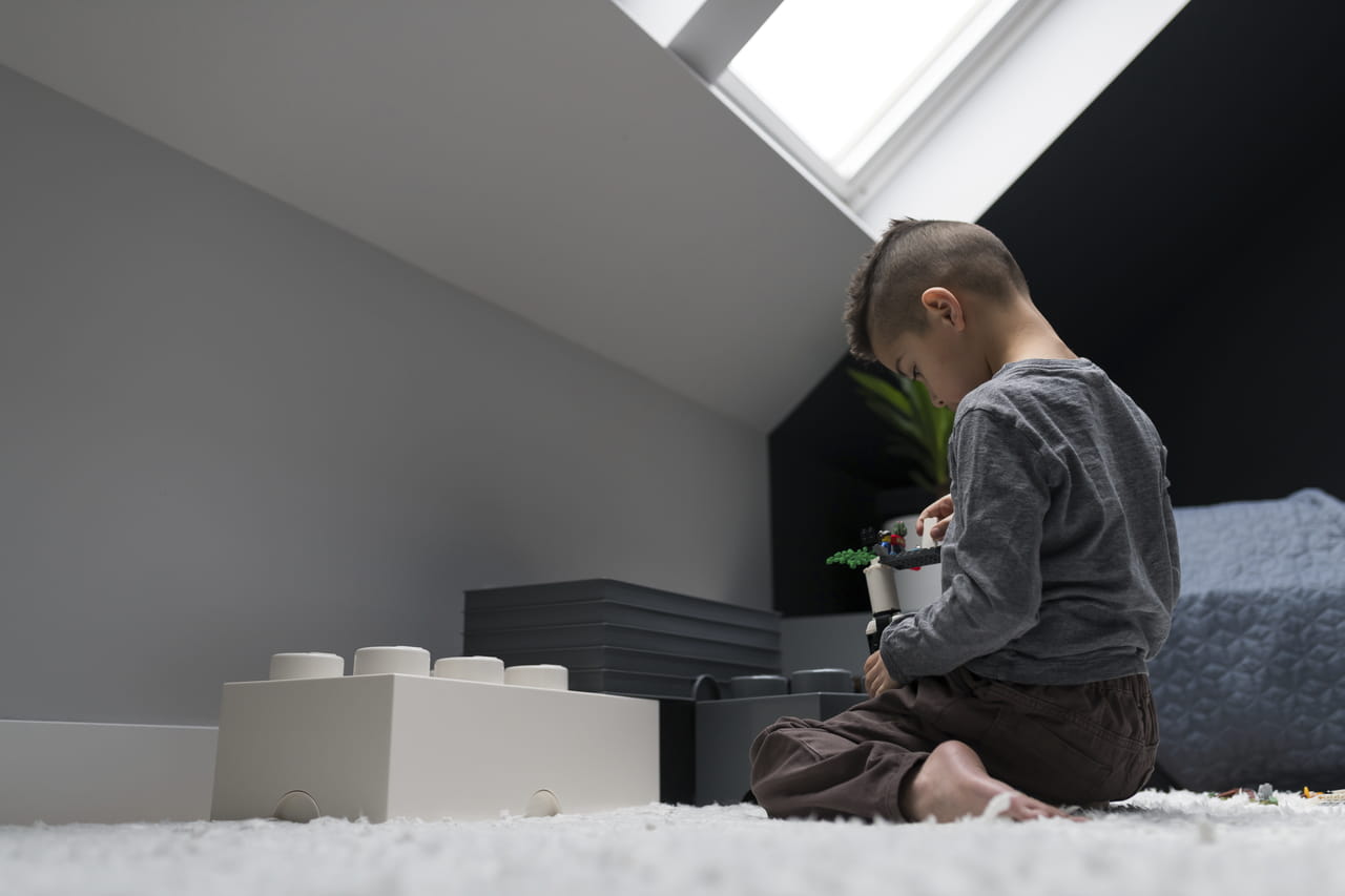 Kind speelt met bouwblokken in een lichte zolderkamer met een VELUX dakvenster.