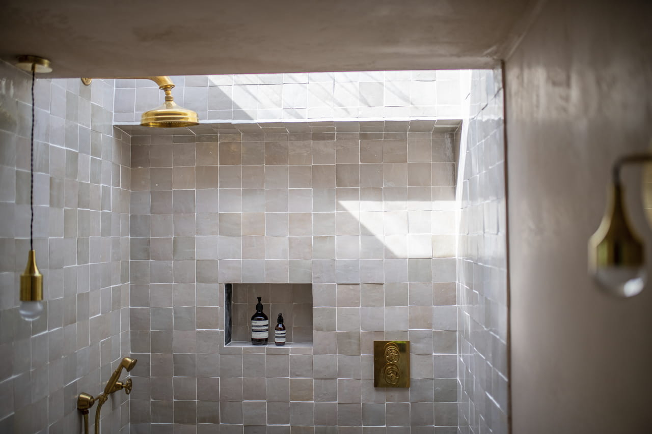 Luxurious bathroom with beige tiles, golden fixtures, and a VELUX skylight.