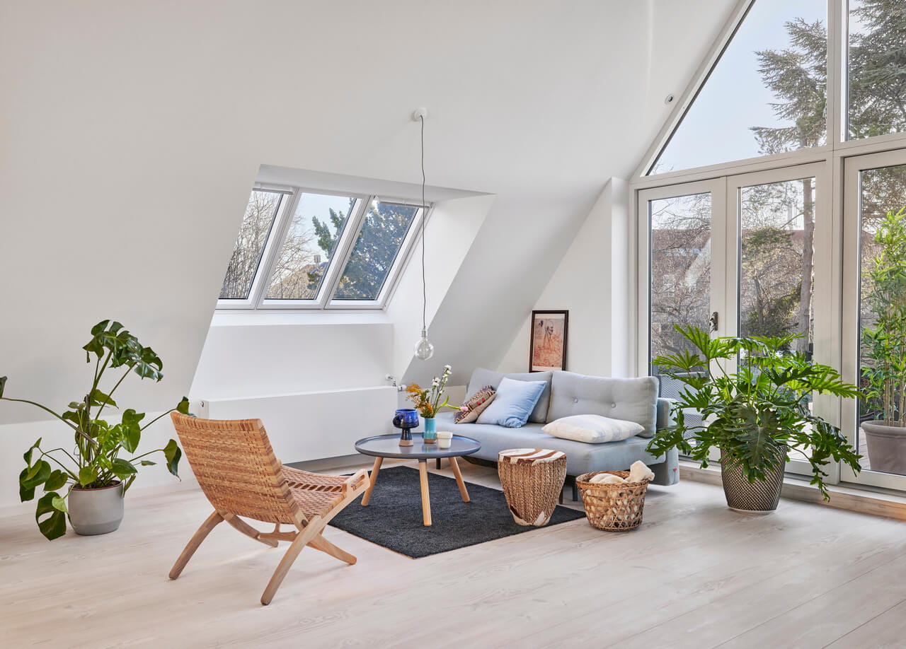 Acogedora sala de estar en el ático con ventanas de tejado VELUX y plantas exuberantes.