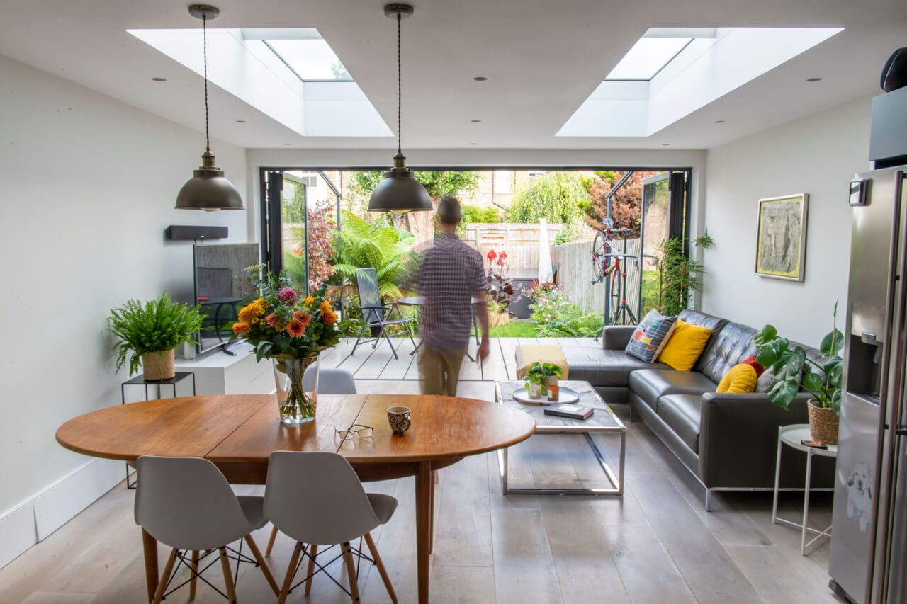Moderne woonkamer met VELUX dakvensters, uitzicht op de tuin en stijlvolle inrichting.