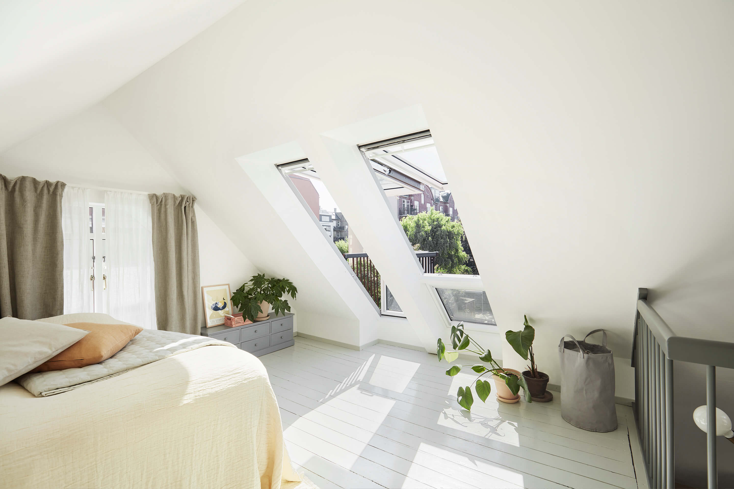 Accogliente camera da letto mansarda con finestre per tetti VELUX e arredamento minimalista.